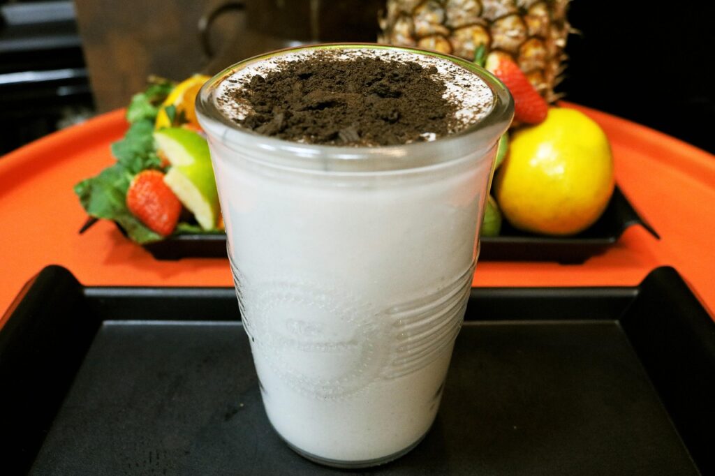 Banana and peanut butter smoothie in a glass with protein powder